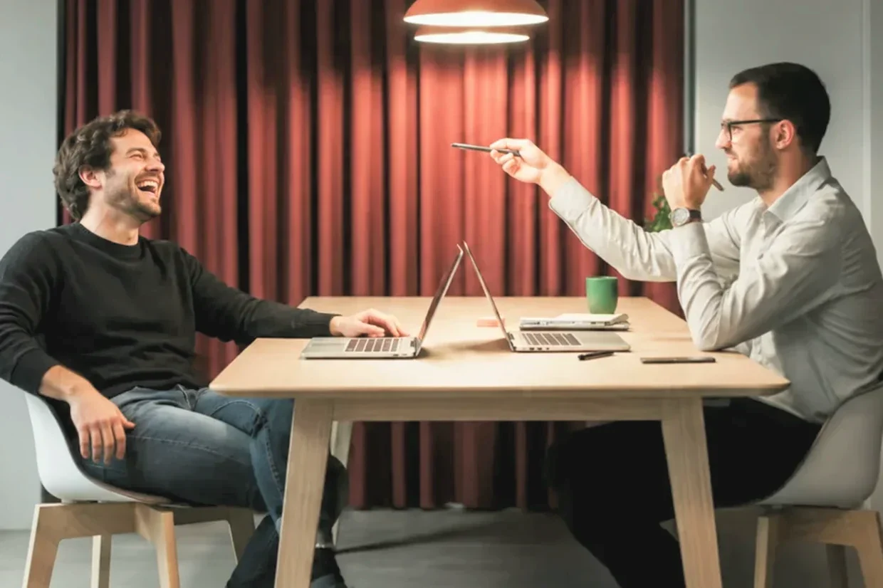 Two consultants laughing together across a table during a working session