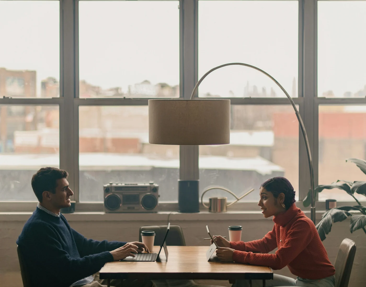 Two partners working through a decision at a table by tall loft windows