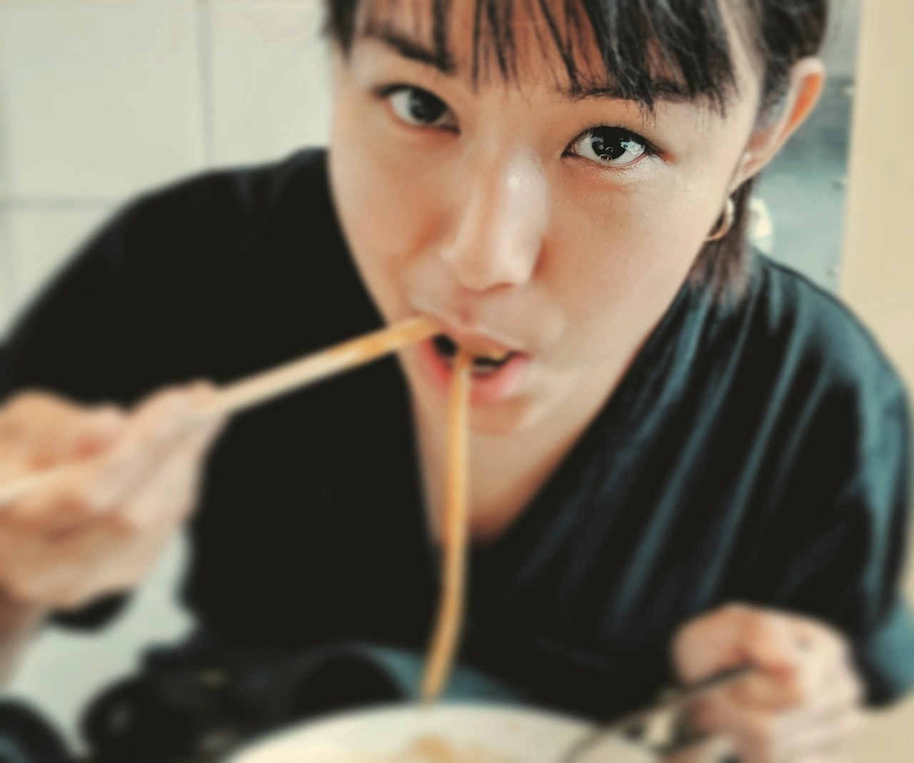 A guest slurps ramen noodles straight from her chopsticks