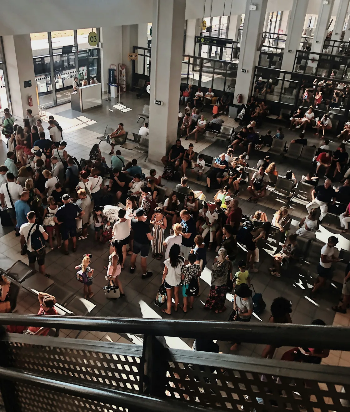 The depot floor seen from the balcony, full of guests between iron columns
