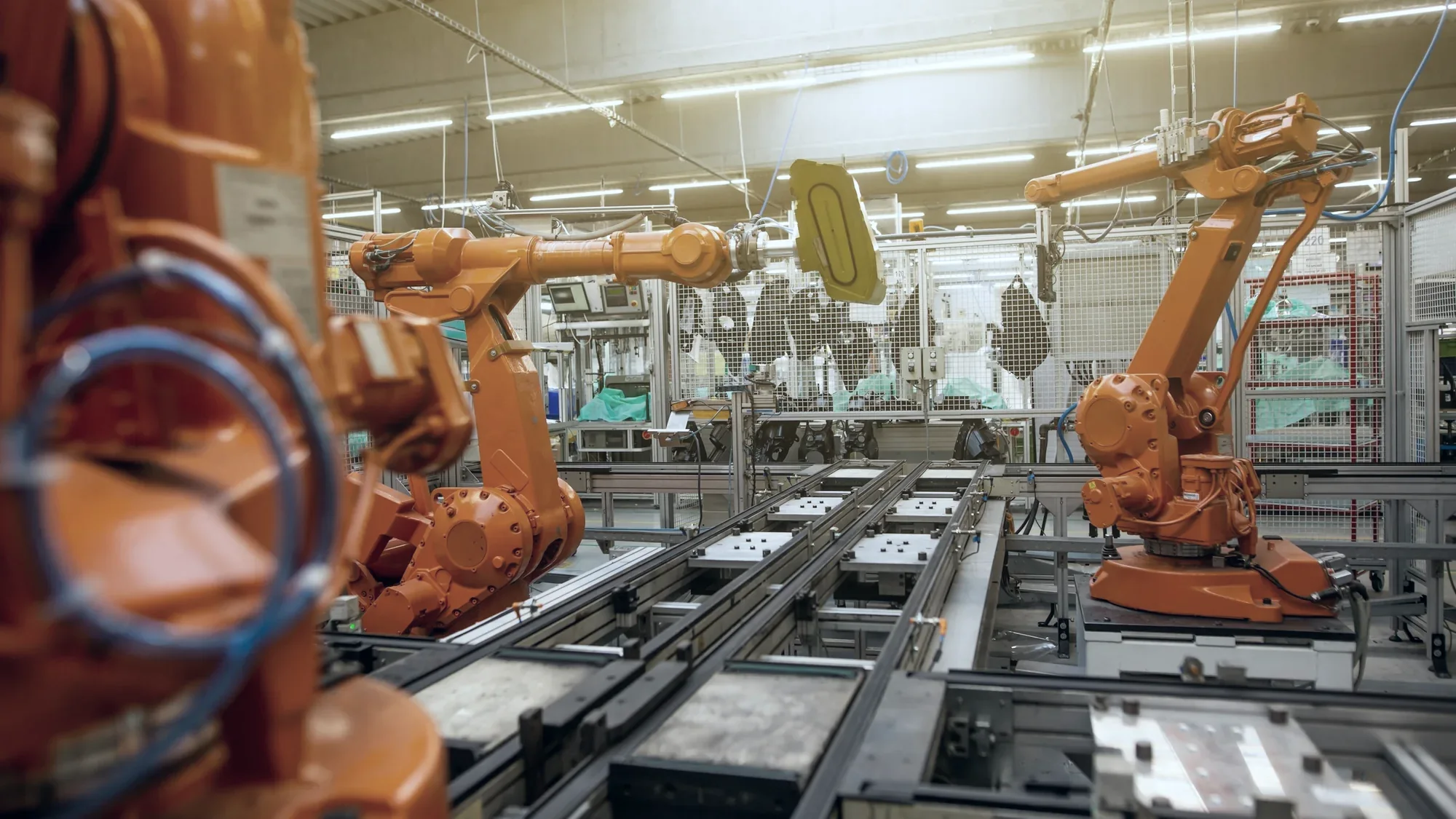 Line of orange robot arms working along an assembly conveyor