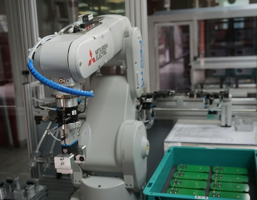White robot arm loading parts from a bin into a machine
