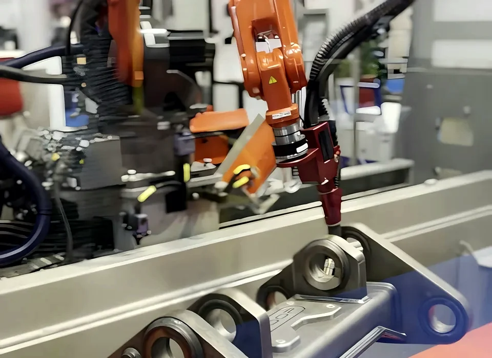 Orange robot welding a steel bracket inside a guarded cell