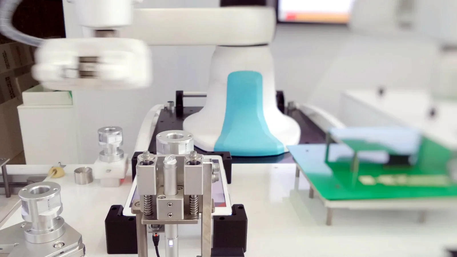 White collaborative robot cell with a gripper and parts fixture