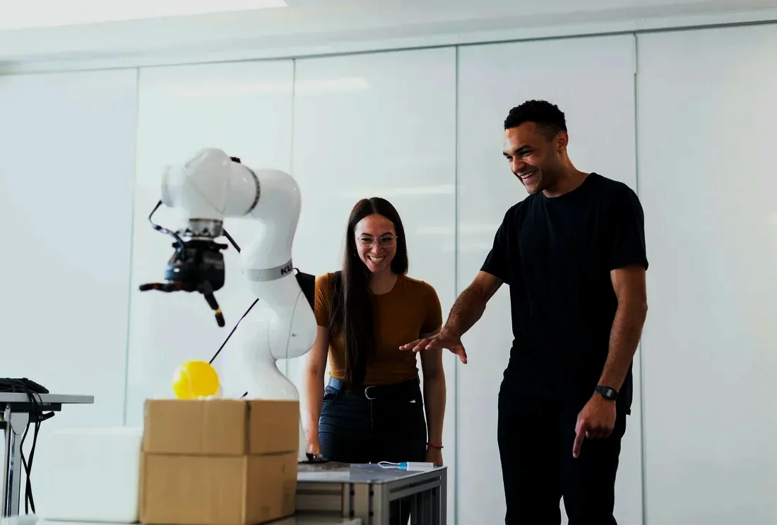 Two engineers smiling as a collaborative robot runs a test pick