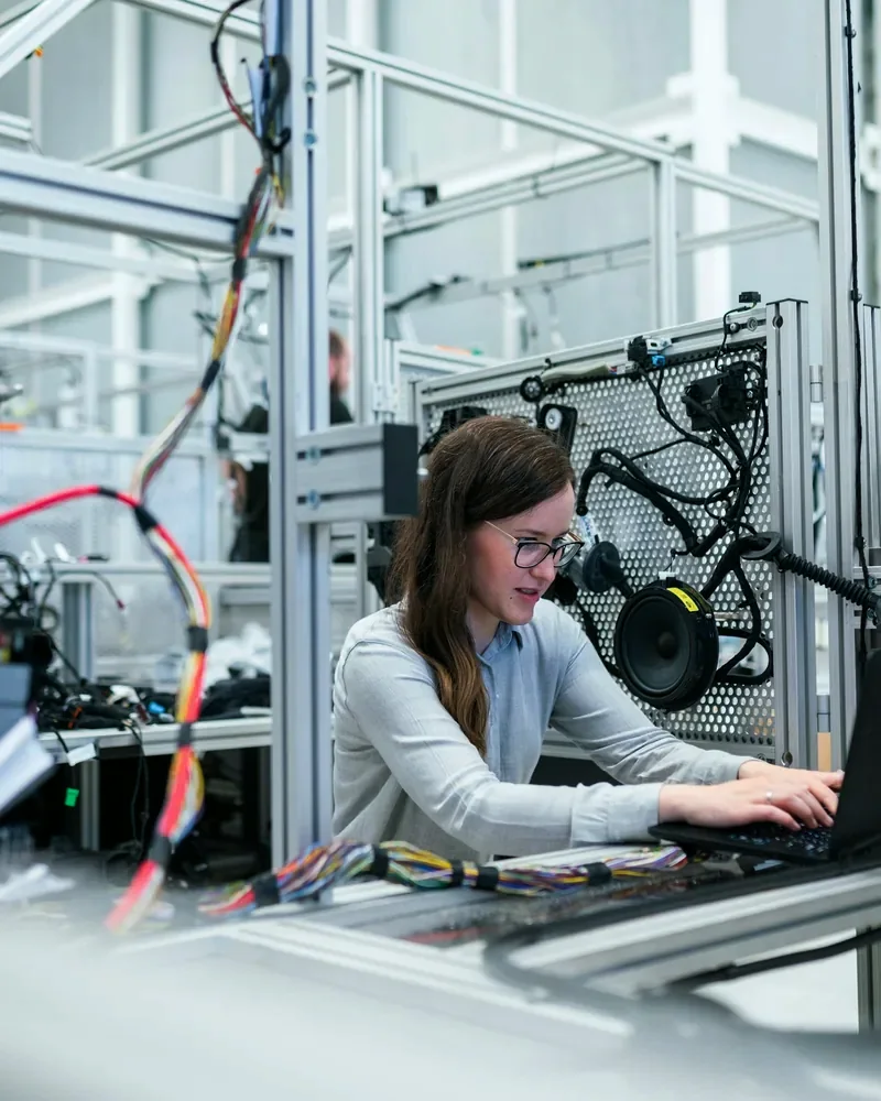 Engineer running a test on a laptop beside a robot cell