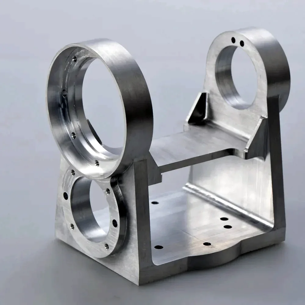Machined titanium bracket with two bores on a grey bench