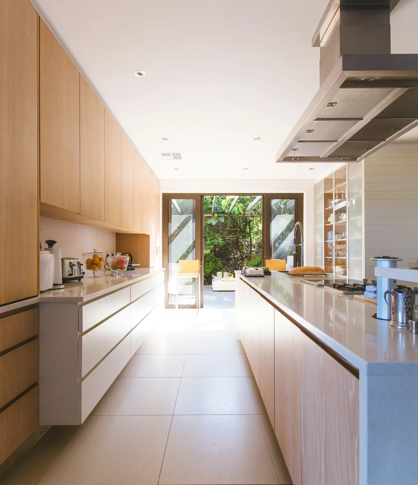 A finished kitchen with pale oak cupboards and a long island, open through glazed doors to the garden