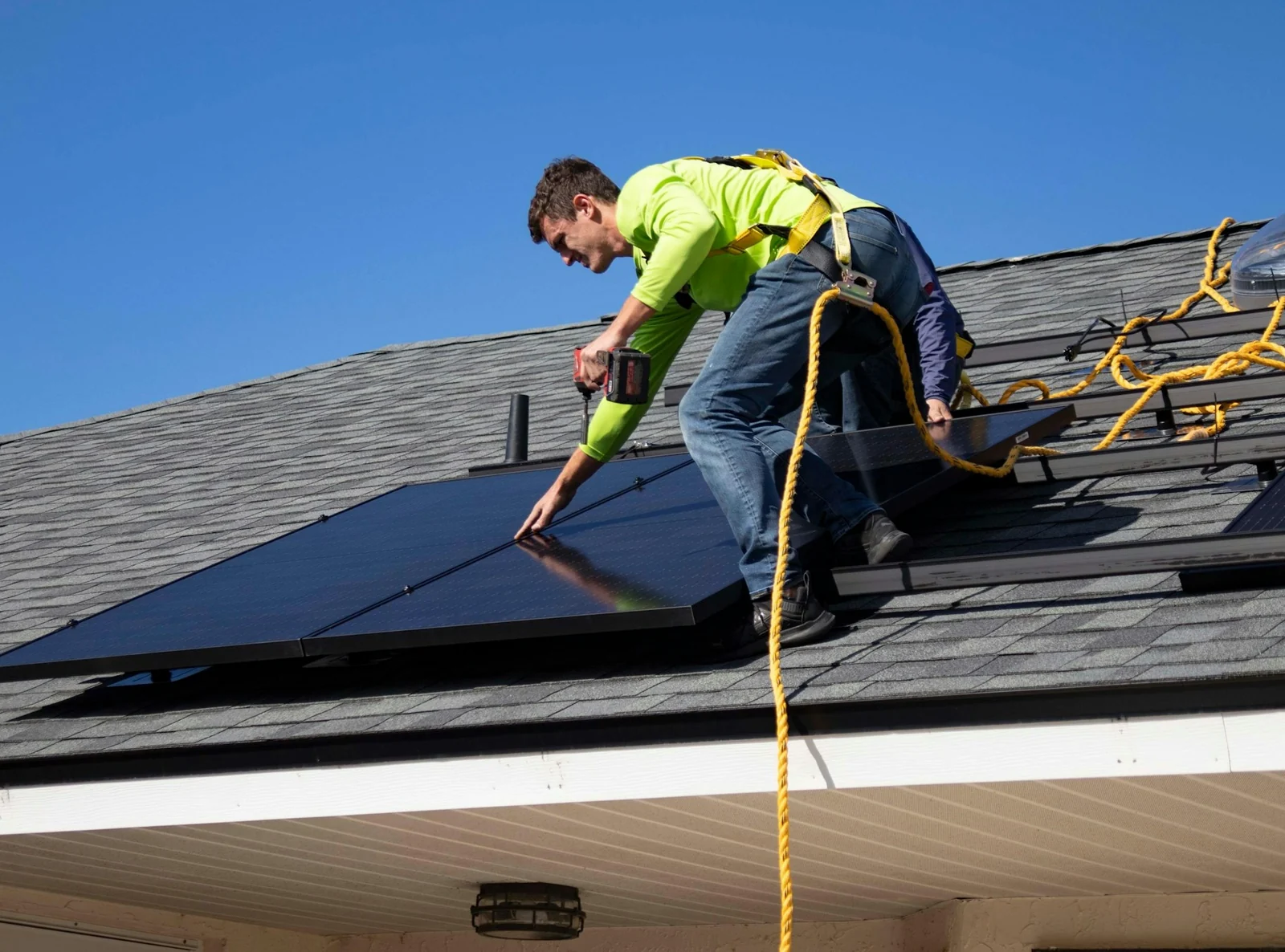 Installer carrying a solar panel across a roof in hard sunlight