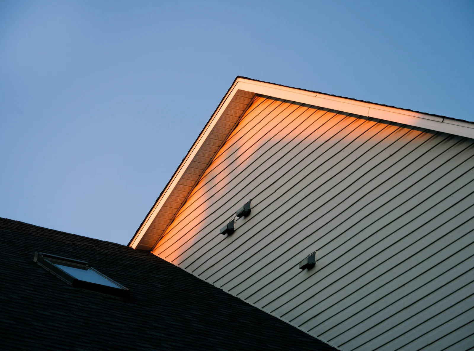 Gable of a home catching the last orange light of the day, skylight on the roof