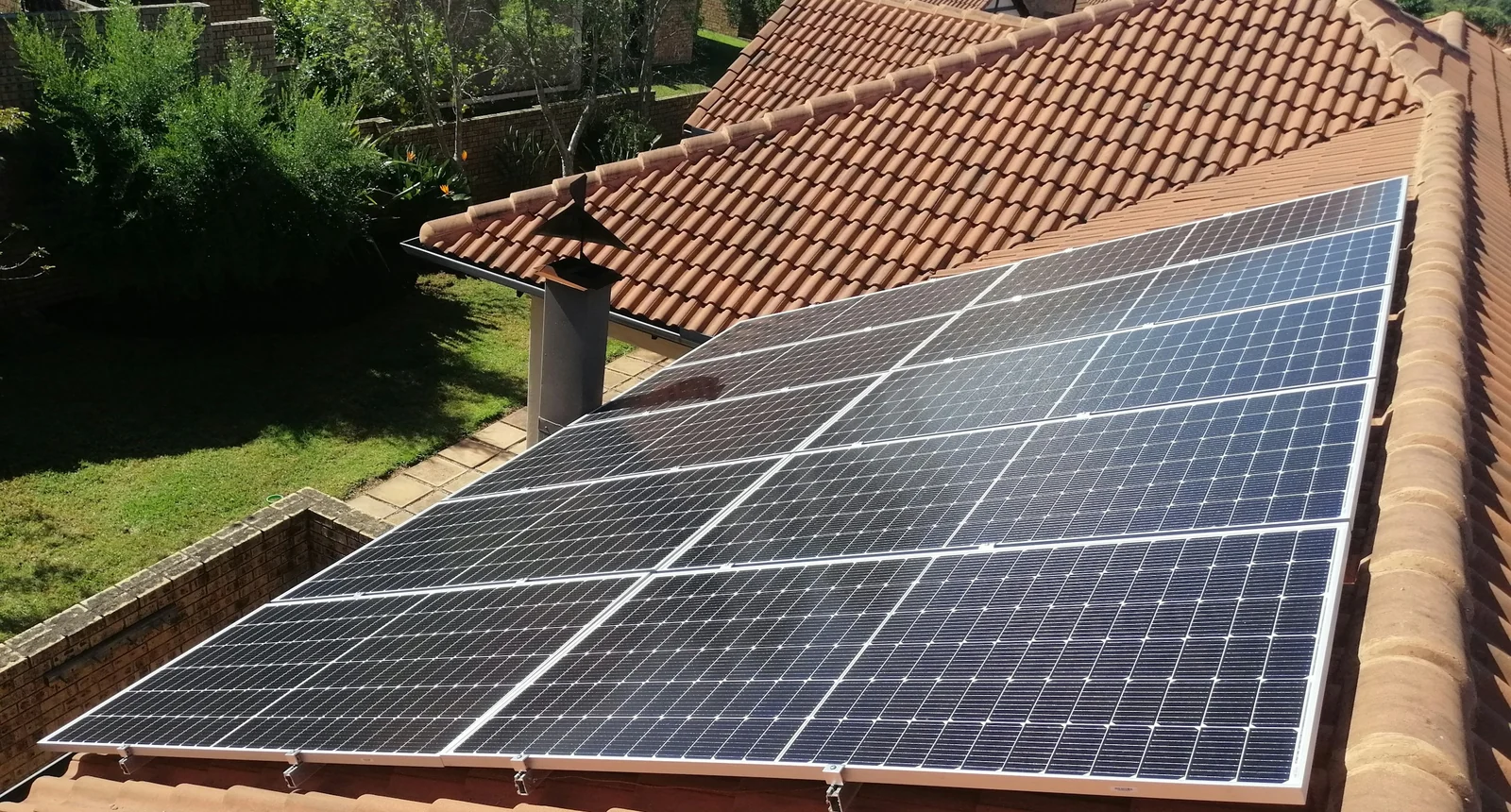 Single-storey desert home with a full rooftop solar array in low golden-hour light, mountains behind