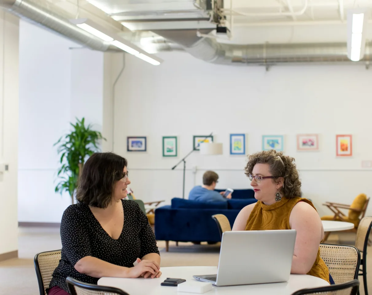 Two founders of a heat-pump company reviewing their data report at a laptop