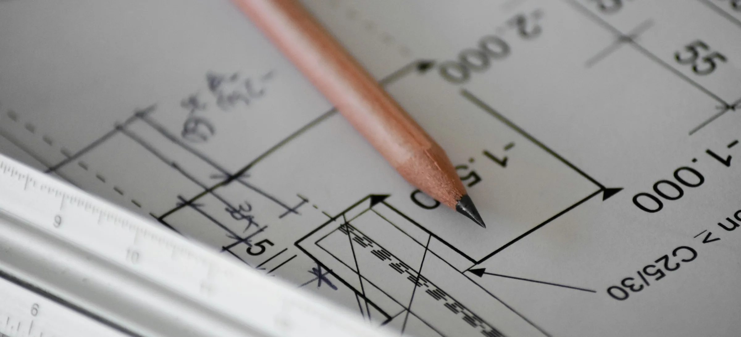 Pencil resting on a hand-measured floor plan on white paper