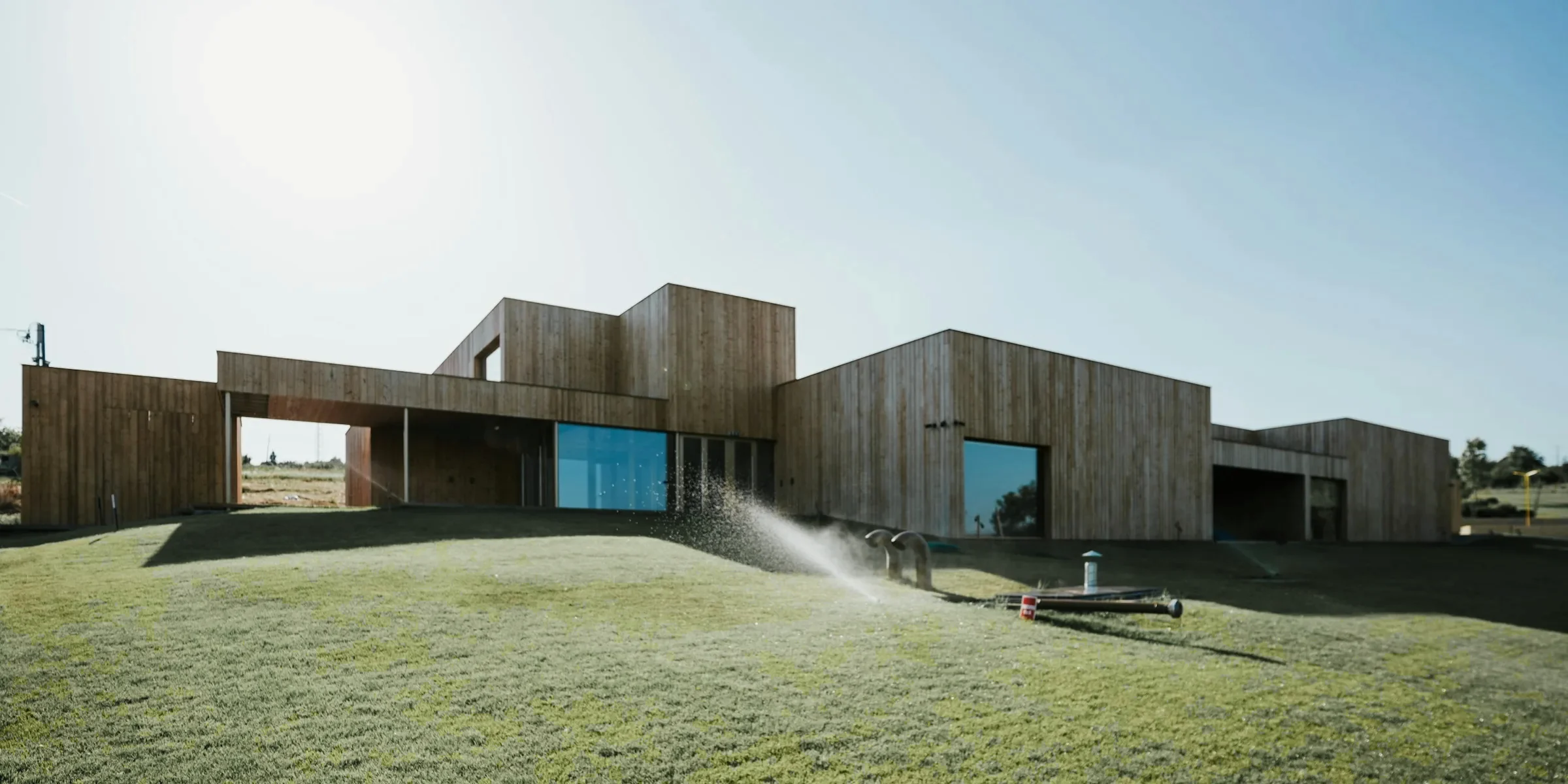 Long low timber school building with large windows on a green lawn in sunshine