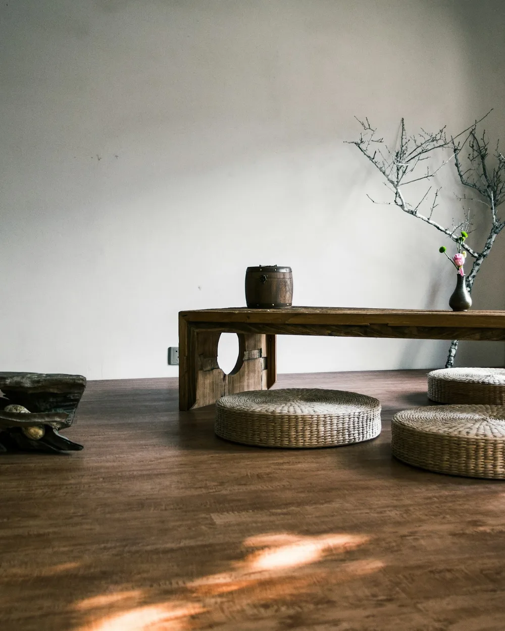 Low oak table and floor cushions on a dark wooden floor, afternoon sun on the boards