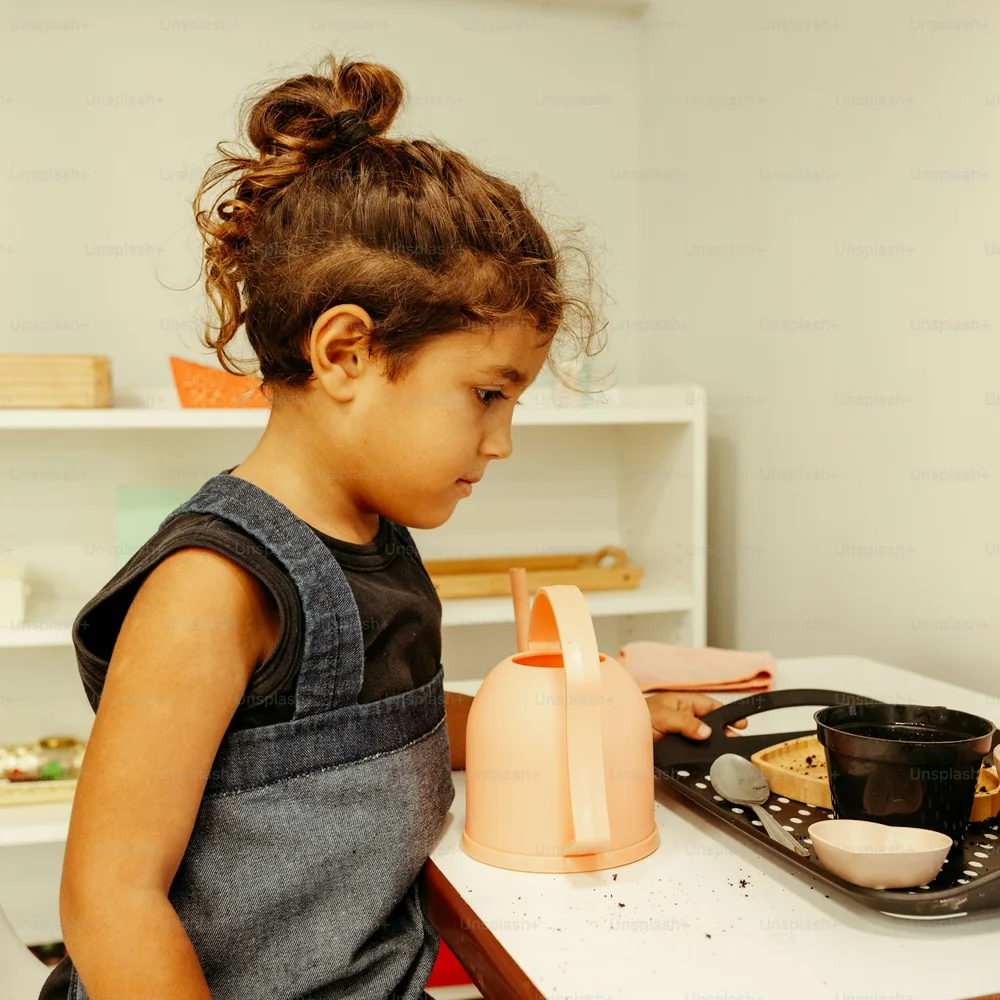 A girl with a watering can prepares a tray of plant pots