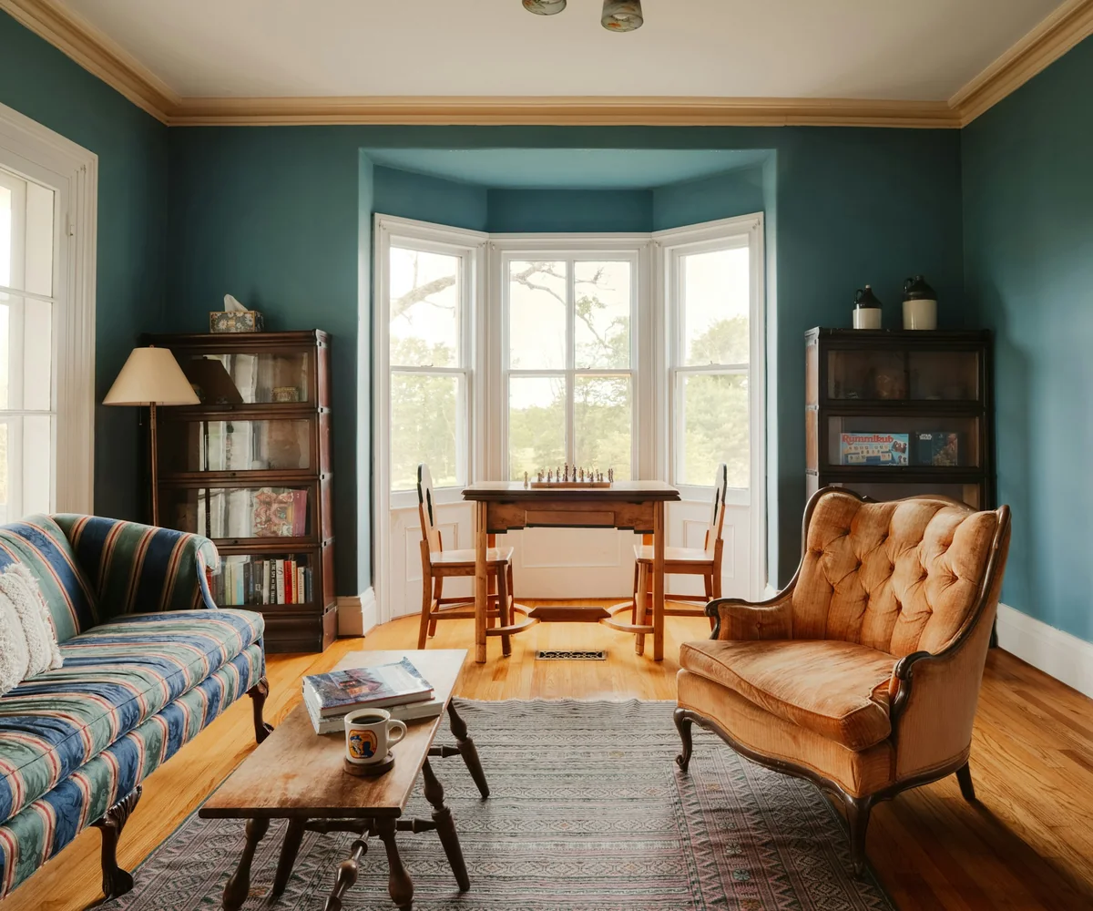 Victorian sitting room with a bay window, teal walls and a wooden floor in daylight