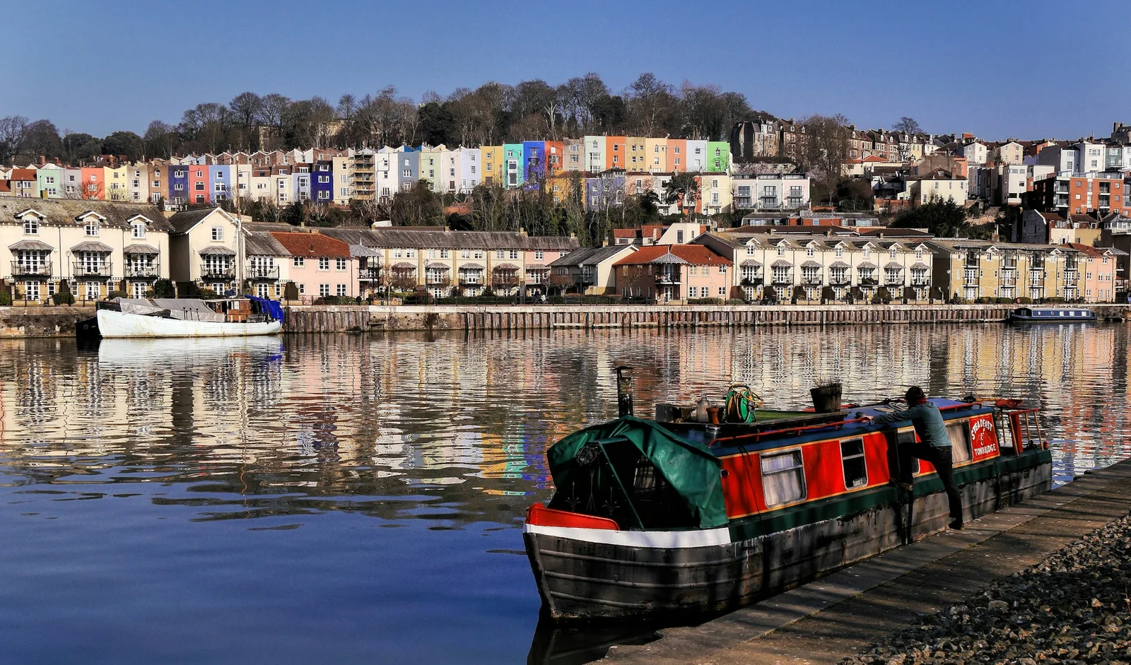 Painted period terraces above Bristol harbour with a narrowboat moored below