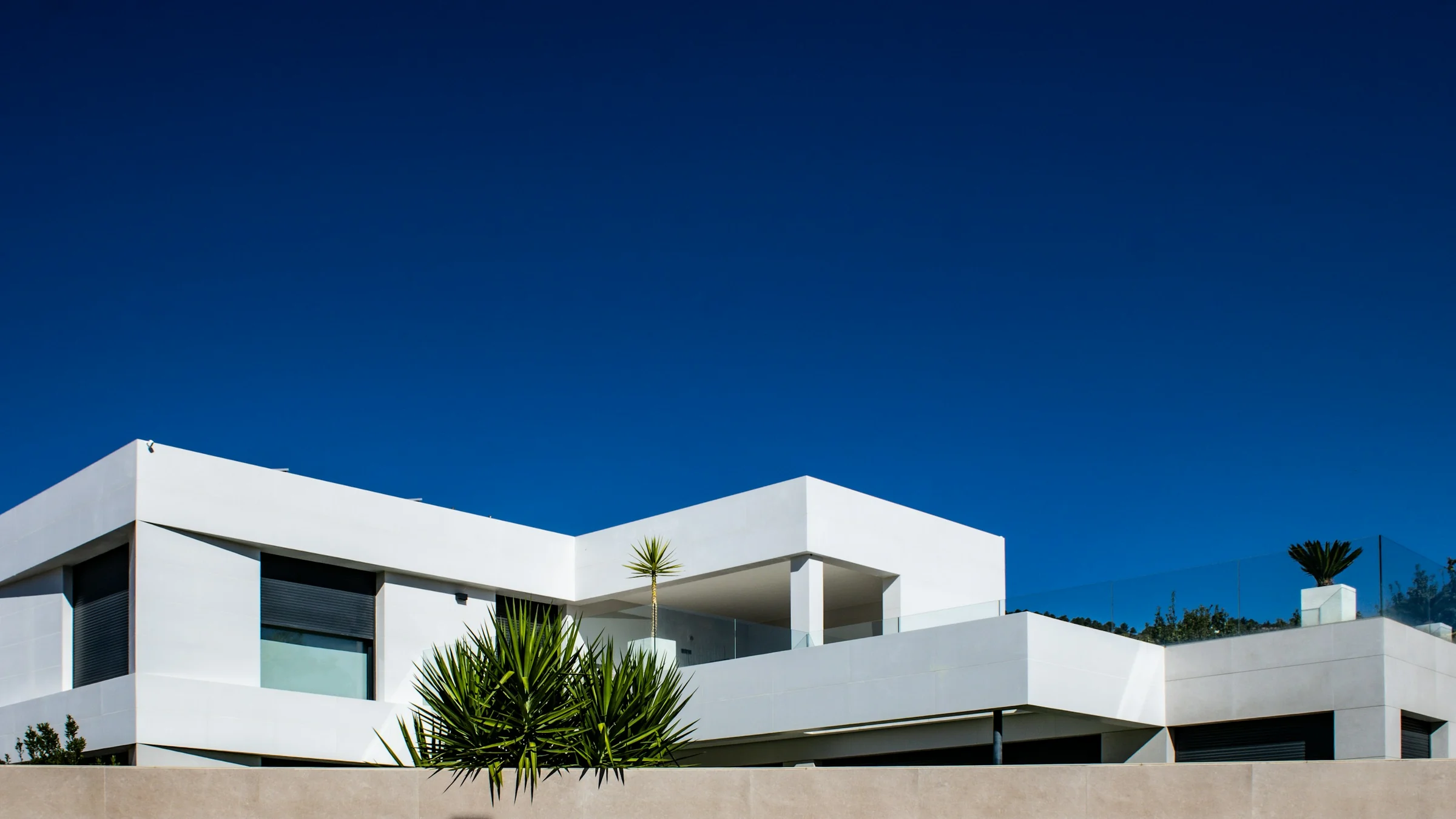 A white modern house with deep terraces under a clear, deep blue sky