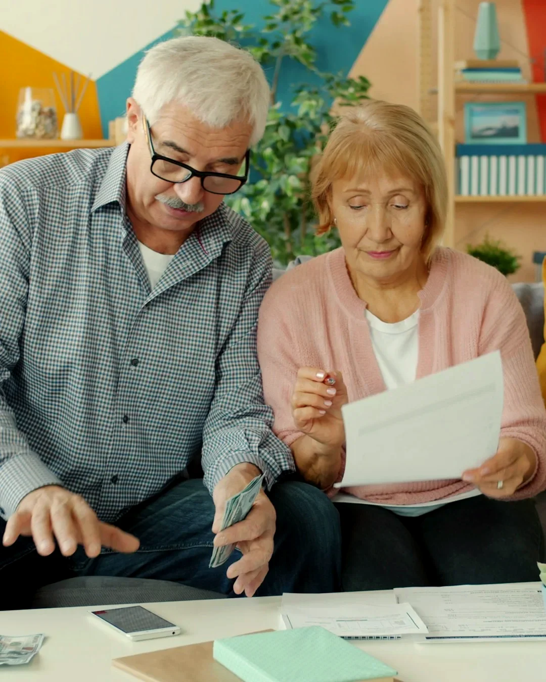 An older couple on their sofa at home, reading through family finance papers together