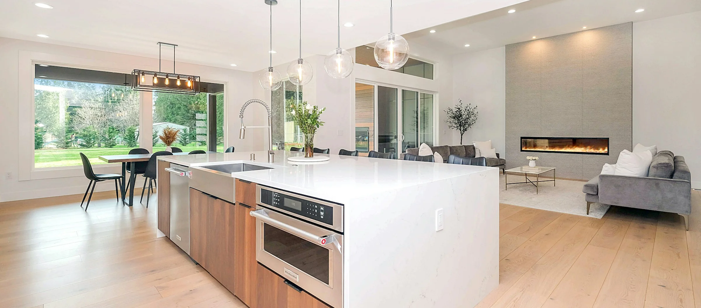 Bright white kitchen and living room, freshly cleaned, with sun on the wood floor