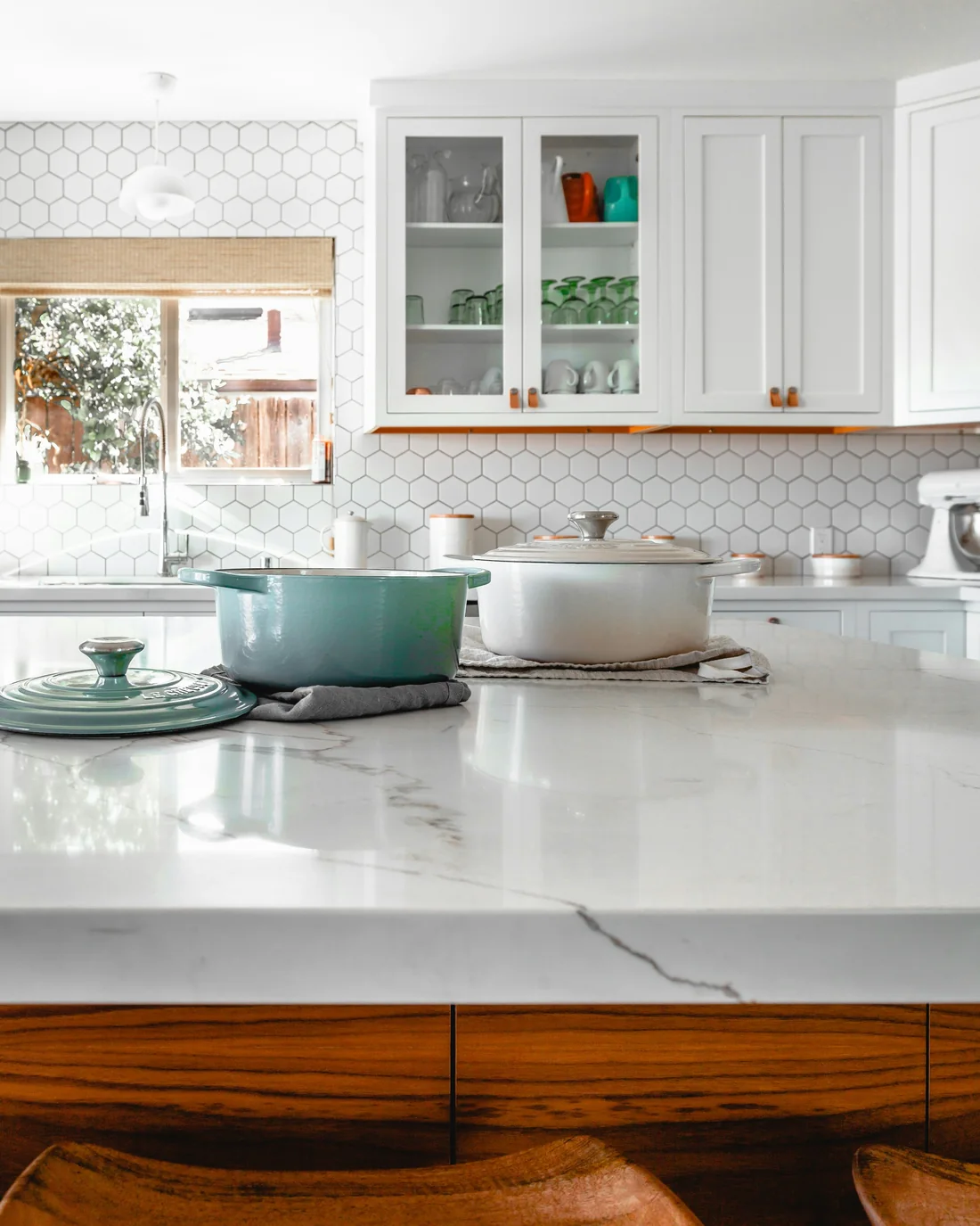 Two cast-iron pots on a white marble benchtop with a warm timber edge
