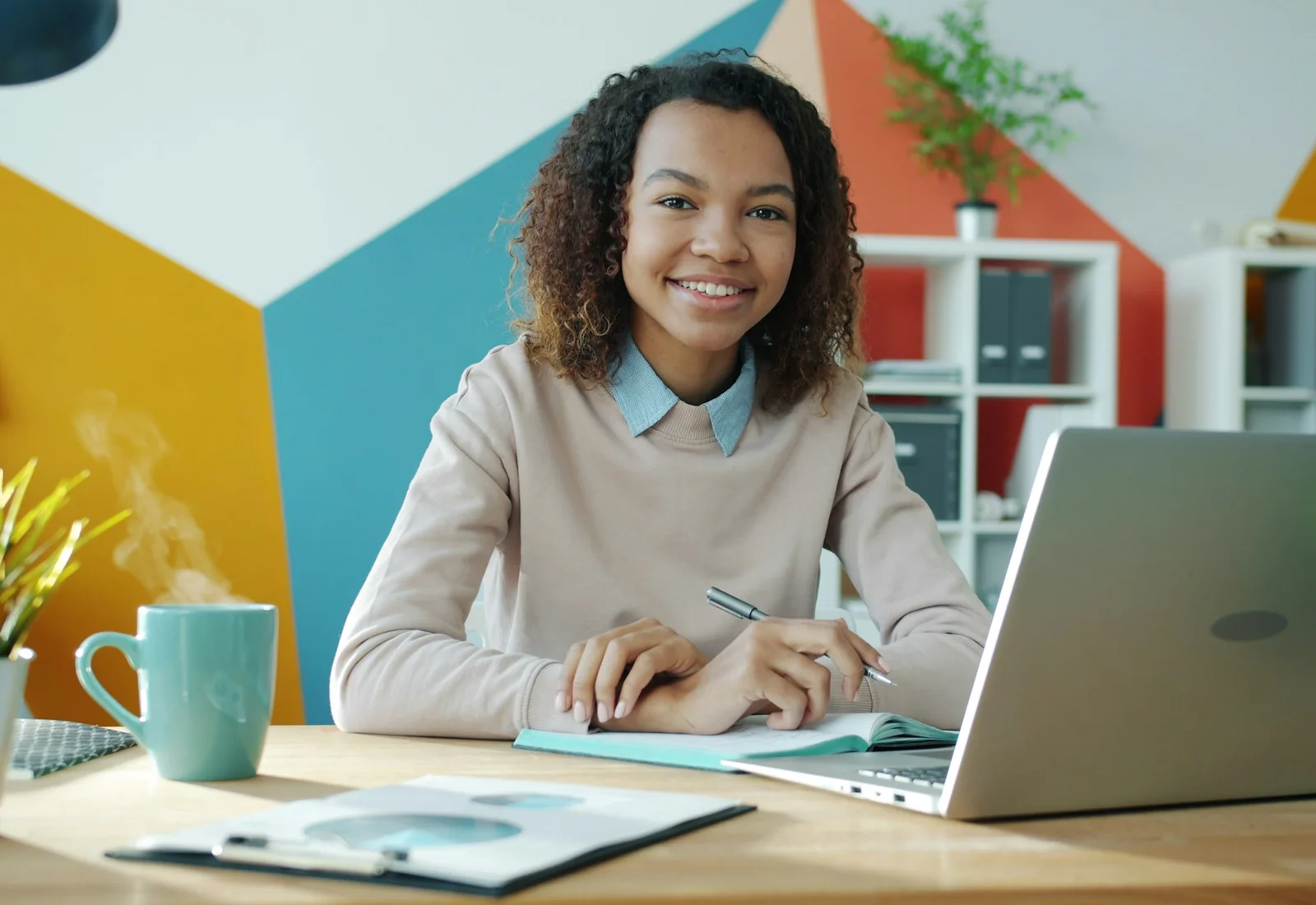 Maya Lindqvist smiling at her desk with a laptop and a mug