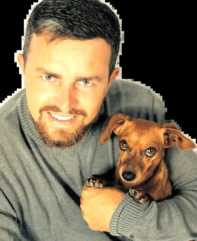 Jonah Pierce smiling with a dachshund in his arms