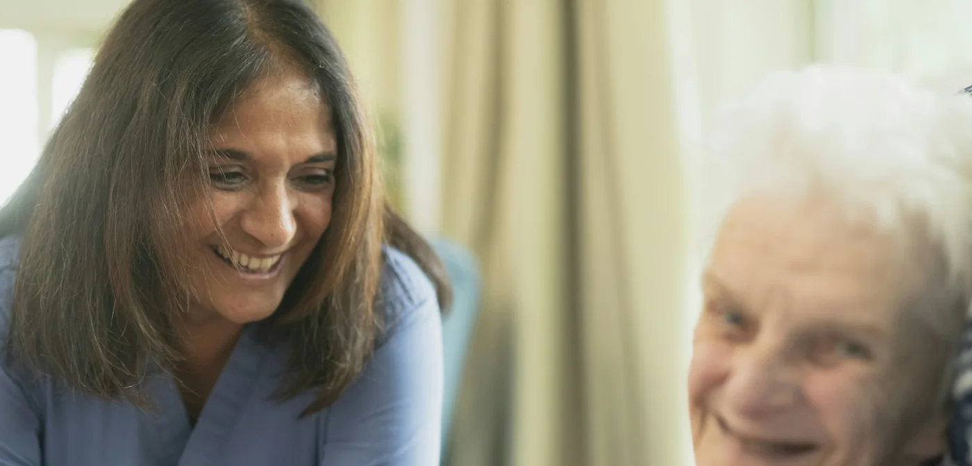 Healthcare assistant laughing with an older woman