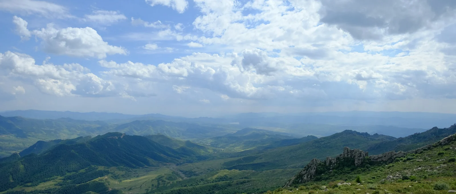 Green mountain valleys under a wide blue sky full of white cloud