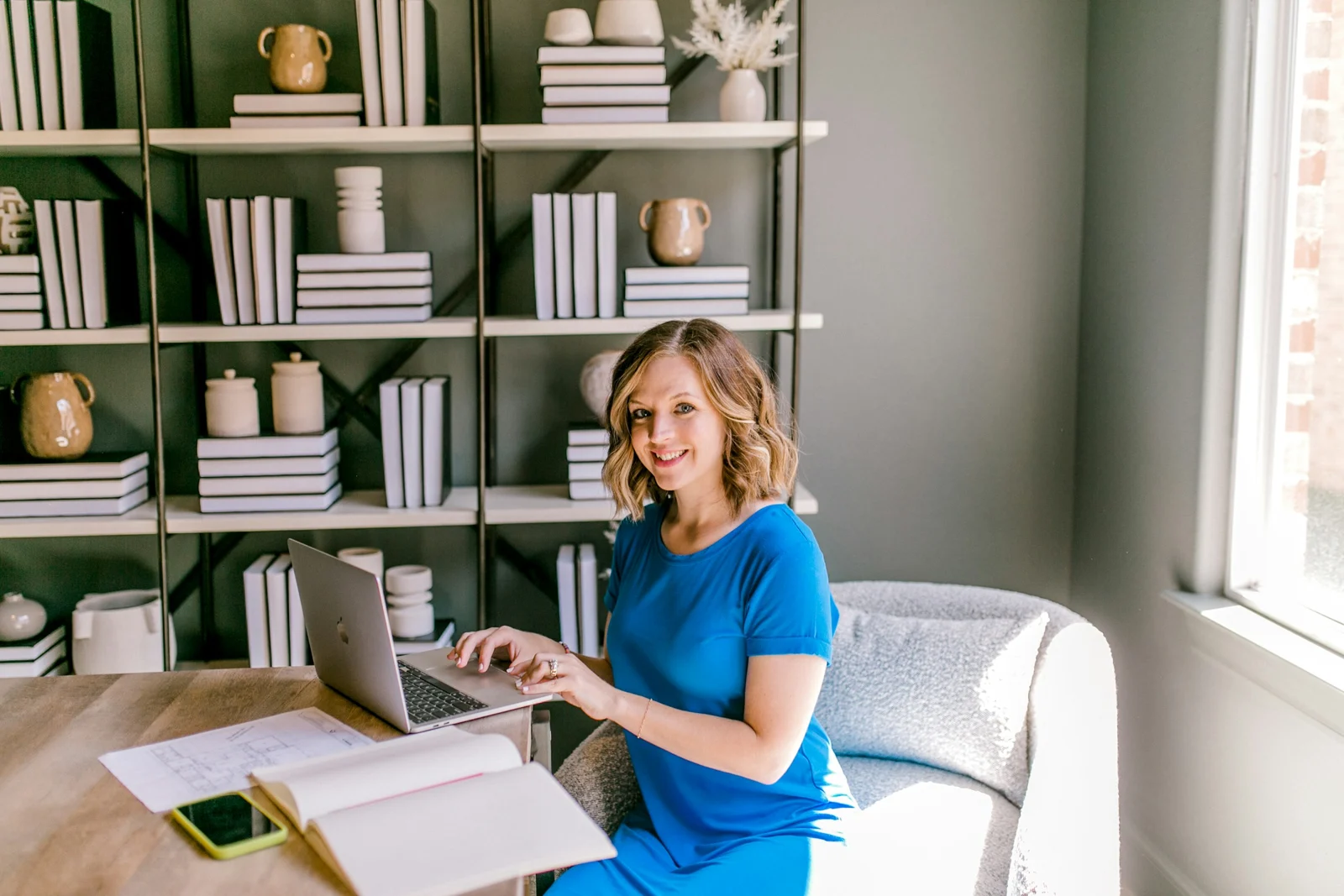 A bookkeeper smiling at her laptop in a bright room with bookshelves